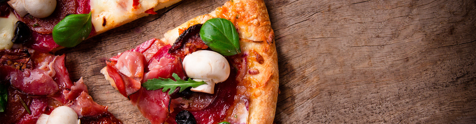 Čerstvá pizza so salámou, šunkou, šampiňónmi a bazalkou